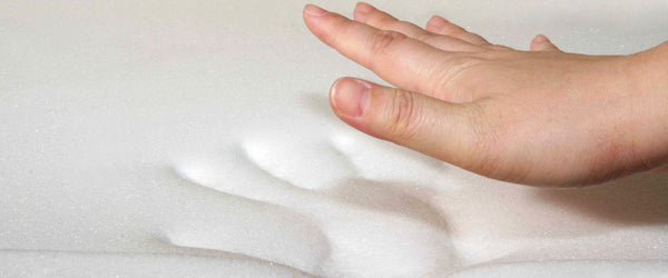 Hand pressing down on a memory foam mattress