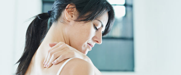 Woman with shoulder pain from sleeping rubbing shoulder