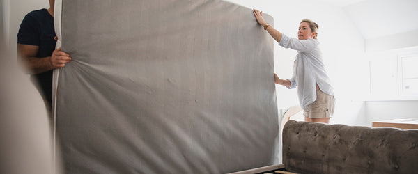 Couple setting up a mattress on bed frame