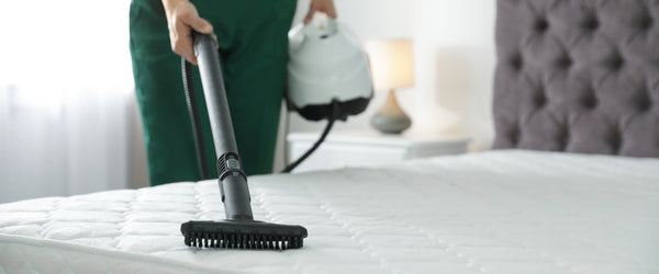 Woman vacuuming mattress surface
