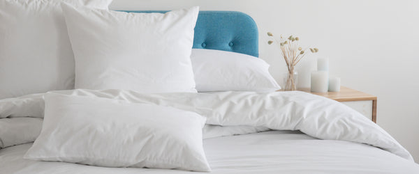 White pillows and sheets on bed with blue headboard