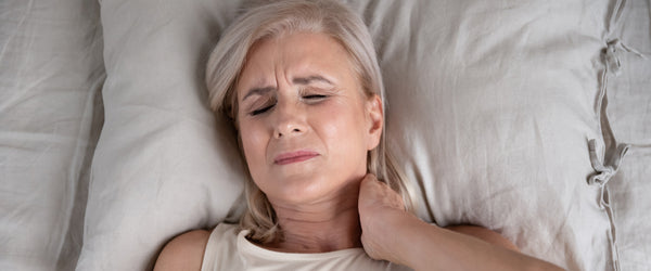 Woman with neck pain laying in bed